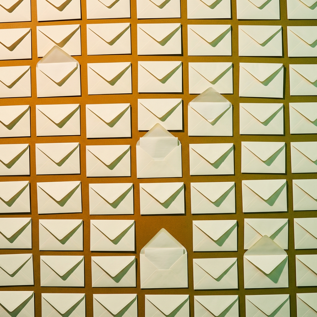 Grid of white envelopes on a brown background with a few open envelopes scattered throughout